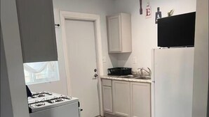 A full kitchen with white cabinets, a stove, and a refrigerator. - Spacious and Private (Bakersfield)