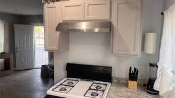 Una cocina moderna con armarios blancos, estufa a gas y una encimera con un bloque de cuchillos.