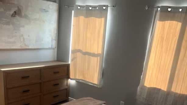 A bedroom with a bed, dresser, and two windows with curtains. - Spacious and Private (Bakersfield)