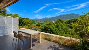 An outdoor patio with a table and chairs, a white sliding door, and a view of a mountainous landscape. - T2 Dolce & Vita B3 with pool (Propriano)