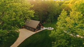A large, single-story cabin with a sloped roof, surrounded by dense forest. - Stillwater Retreat | Pickleball Court + Private Pond w/ Kayaking (Big Prairie)