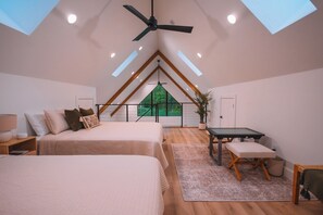 A bedroom with two beds, a desk, and a view of a green landscape through a skylight. - Stillwater Retreat | Pickleball Court + Private Pond w/ Kayaking (Big Prairie)