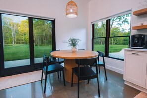 A modern kitchen with a round wooden table, black chairs, and a potted plant. - Stillwater Retreat | Pickleball Court + Private Pond w/ Kayaking (Big Prairie)