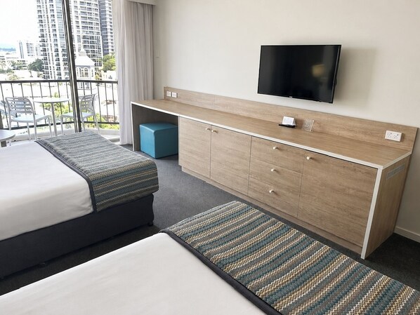 Una habitación de hotel con cama, escritorio, televisor y vista a la ciudad.