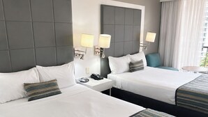 Et hotelværelse med to senge, sengeborde, en telefon og udsigt til det fri.