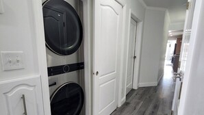 A laundry room with two stacked washers and dryers, white cabinetry, and a wooden floor.