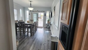 A spacious kitchen with wooden cabinets, a dining area with a table and chairs, and a view of the backyard through the open door.
