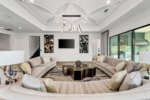 Un salon moderne avec un canapé d’angle, une table basse en verre et un téléviseur à écran plat fixé au mur.