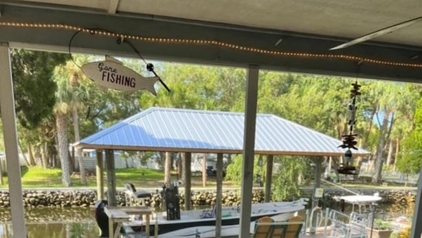 Un espace extérieur aménagé en terrasse, avec un coin salon couvert, un petit étang et un kiosque.
