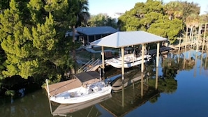 Un port de plaisance doté d’un quai abrité, d’une maison et entouré d’arbres.
