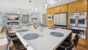 Een moderne keuken met roestvrijstalen apparatuur, een eetgedeelte met een groot kookeiland, en een woonkamer met een open haard.