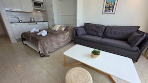 Ein modernes Wohnzimmer mit Sofa, Couchtisch und Bett mit Decke.