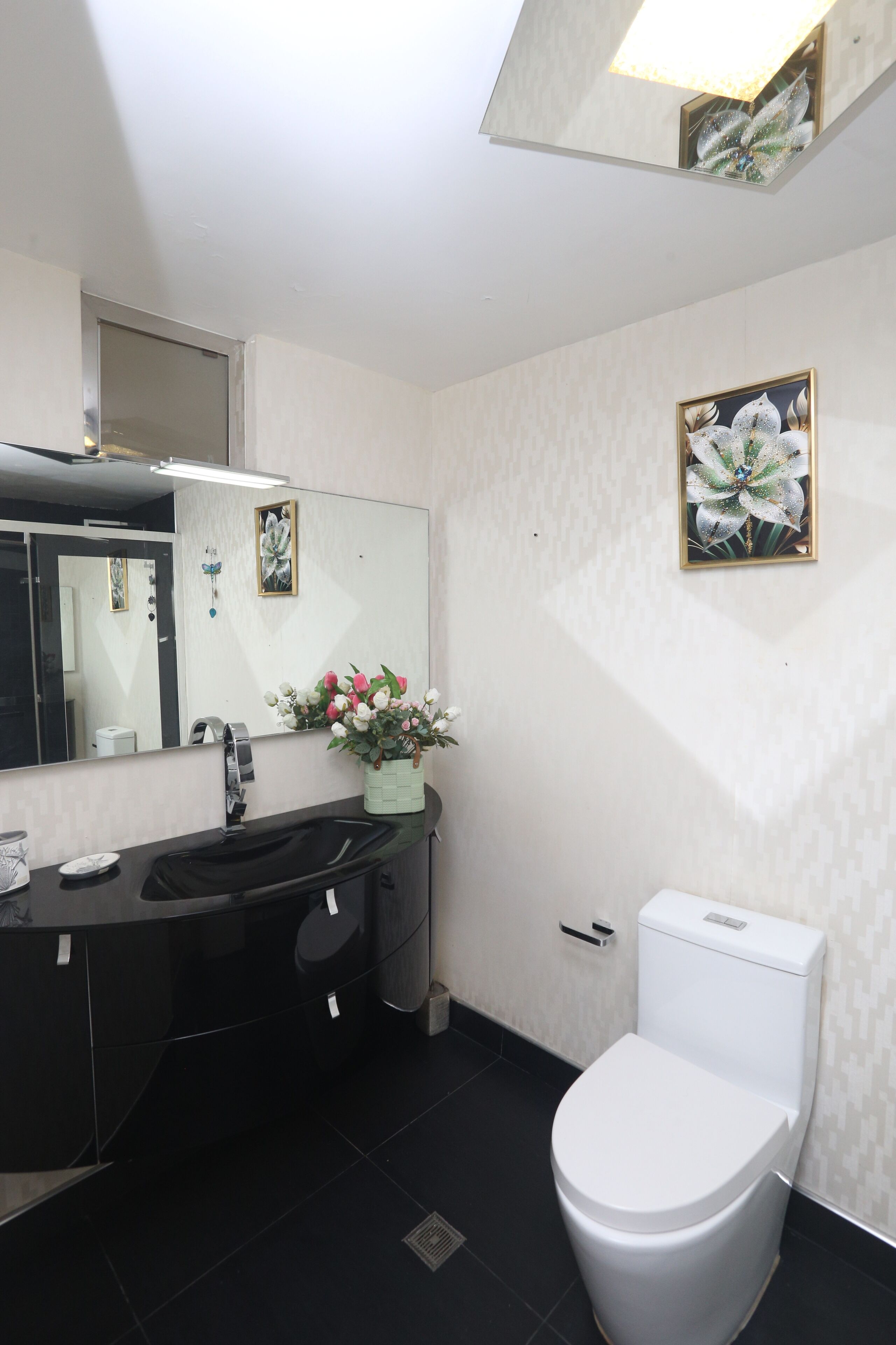 Een badkamer met een zwart wastafel, wit toilet en een spiegel boven de wastafel.