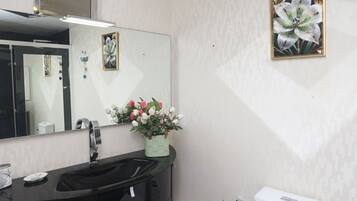 Een badkamer met een zwart wastafel, wit toilet en een spiegel boven de wastafel.