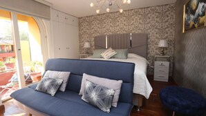 Un dormitorio con cama, sofá, mesita de noche y una silla.