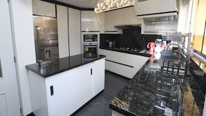 Una cocina moderna con armarios blancos, encimeras negras, horno integrado y microondas.