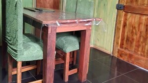 Une table à manger en bois avec des chaises, un téléviseur fixé au mur et une porte en bois.