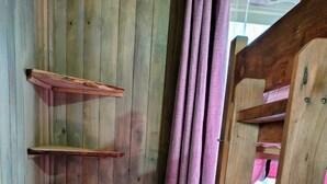 Une pièce d’angle avec des murs en bois, une échelle en bois et un rideau violet.