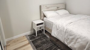 Une chambre à coucher avec un lit, une table de chevet et un tapis.