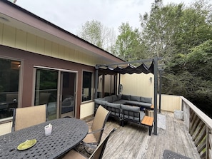 A covered outdoor seating area with a table and chairs, a built-in bench, and a pergola structure.