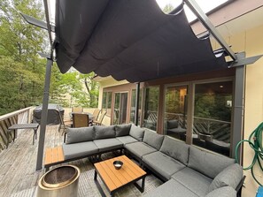 An outdoor patio with a sectional sofa, a small table, and a grill.