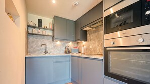 Een moderne keuken met grijze kastjes, een roestvrijstalen oven en een marmeren spatwand.