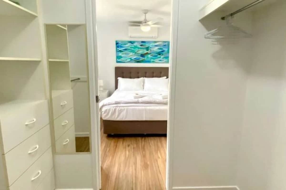 A bedroom with a bed, a ceiling fan, and a wall art piece.