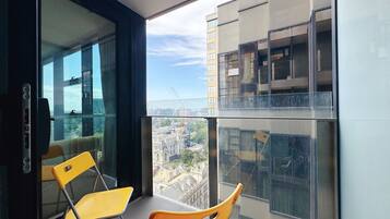 A modern apartment with large windows, a balcony, and a view of the cityscape.