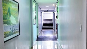 A long, well-lit hallway with a tiled floor, leading to a staircase and a door marked "SAÍDA". - Bandeirantes Hotel (Cuiaba)