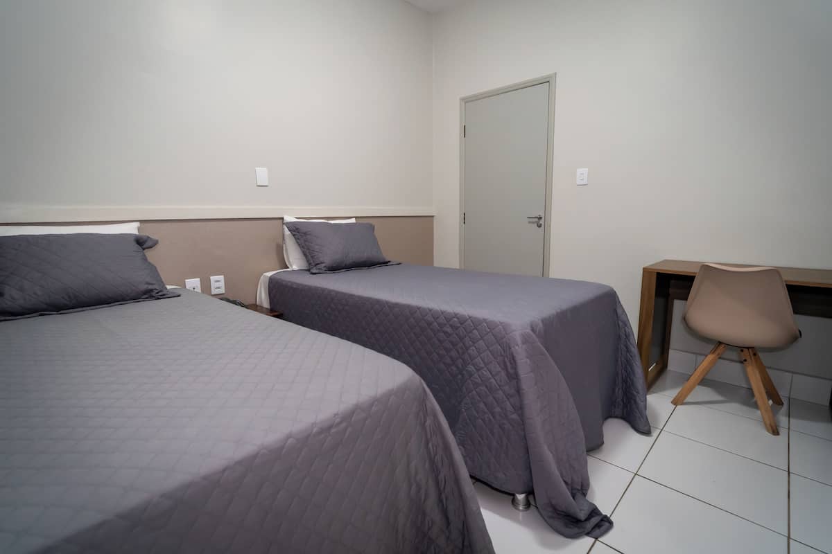 A room with two beds, a desk, and a chair.