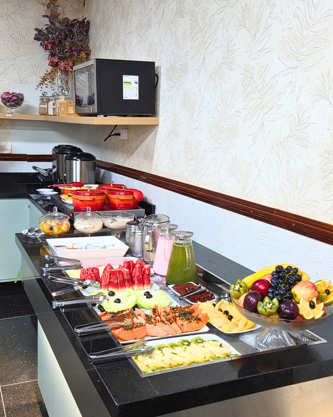 A buffet with various food items including fruits, vegetables, and beverages.