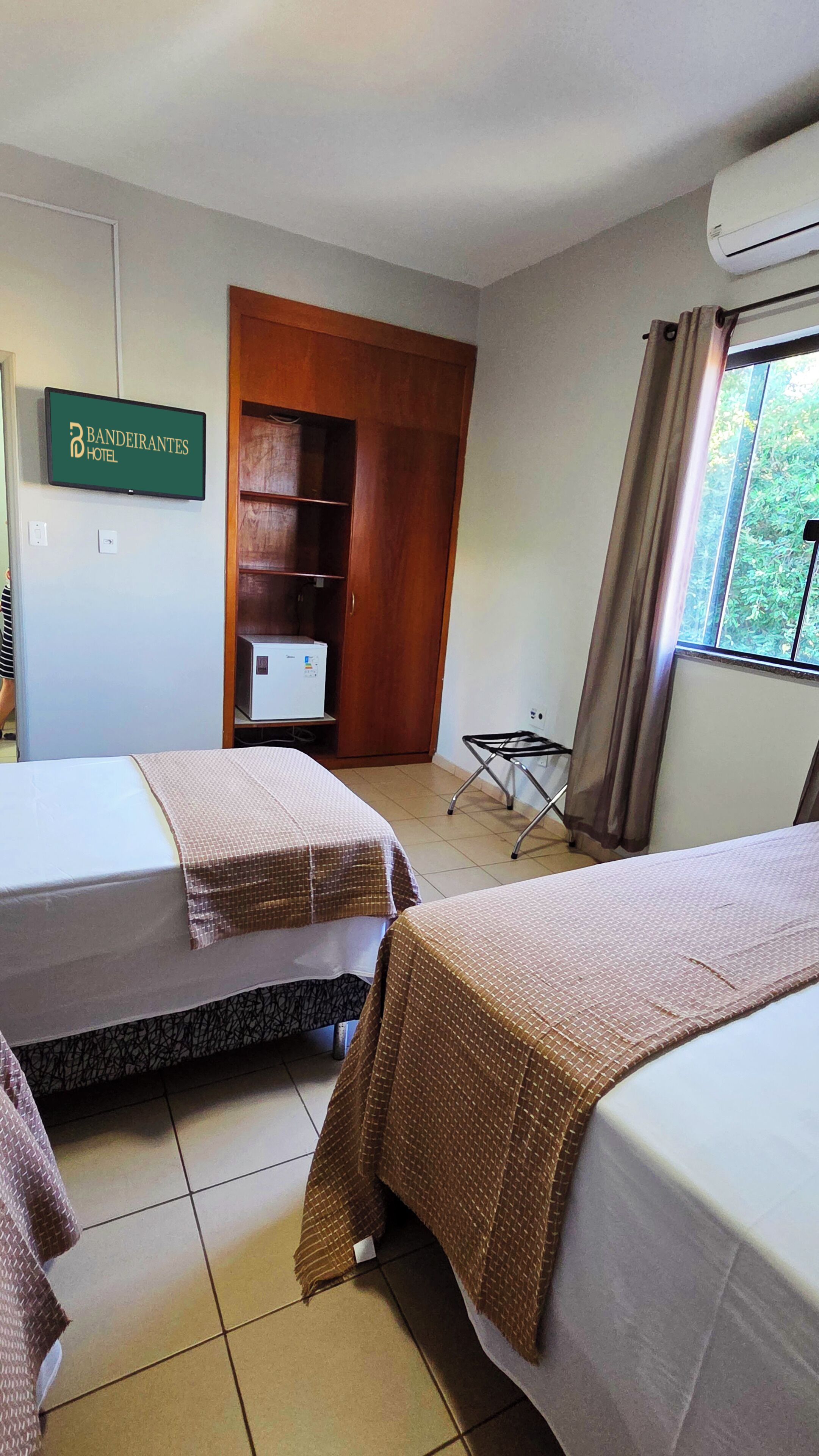 Une chambre d’hôtel avec deux lits, une armoire, un bureau et un téléviseur.