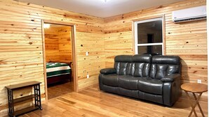 Een kamer met houten paneelwanden, een leren bank, een kleine tafel en een raam.