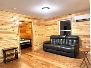 A room with wooden panel walls, a leather sofa, a small table, and a window.