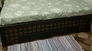 A bed with a floral-patterned bedspread and a dark headboard.