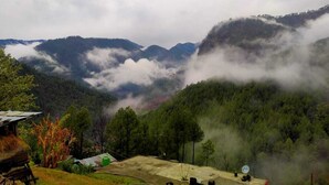 A mountainous landscape with a view of a valley and a small building with a satellite dish.