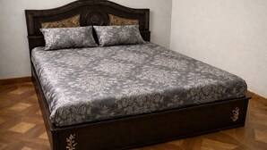 A bed with a dark wooden frame and a floral-patterned bedspread.