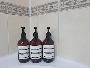Tres botellas de gel de baño, champú y acondicionador sobre un lavamanos.