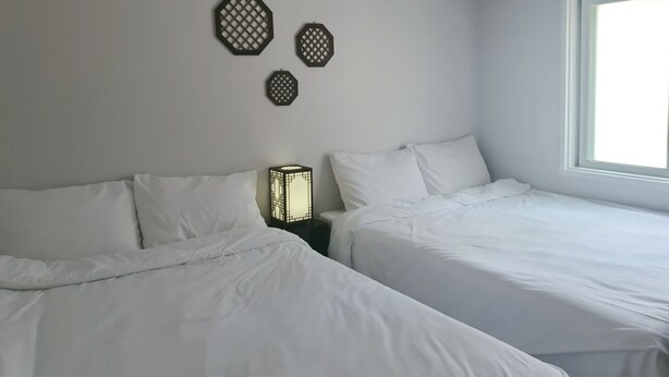 A hotel room with two beds, a window, and decorative wall art. - Liebe stay (Busan)