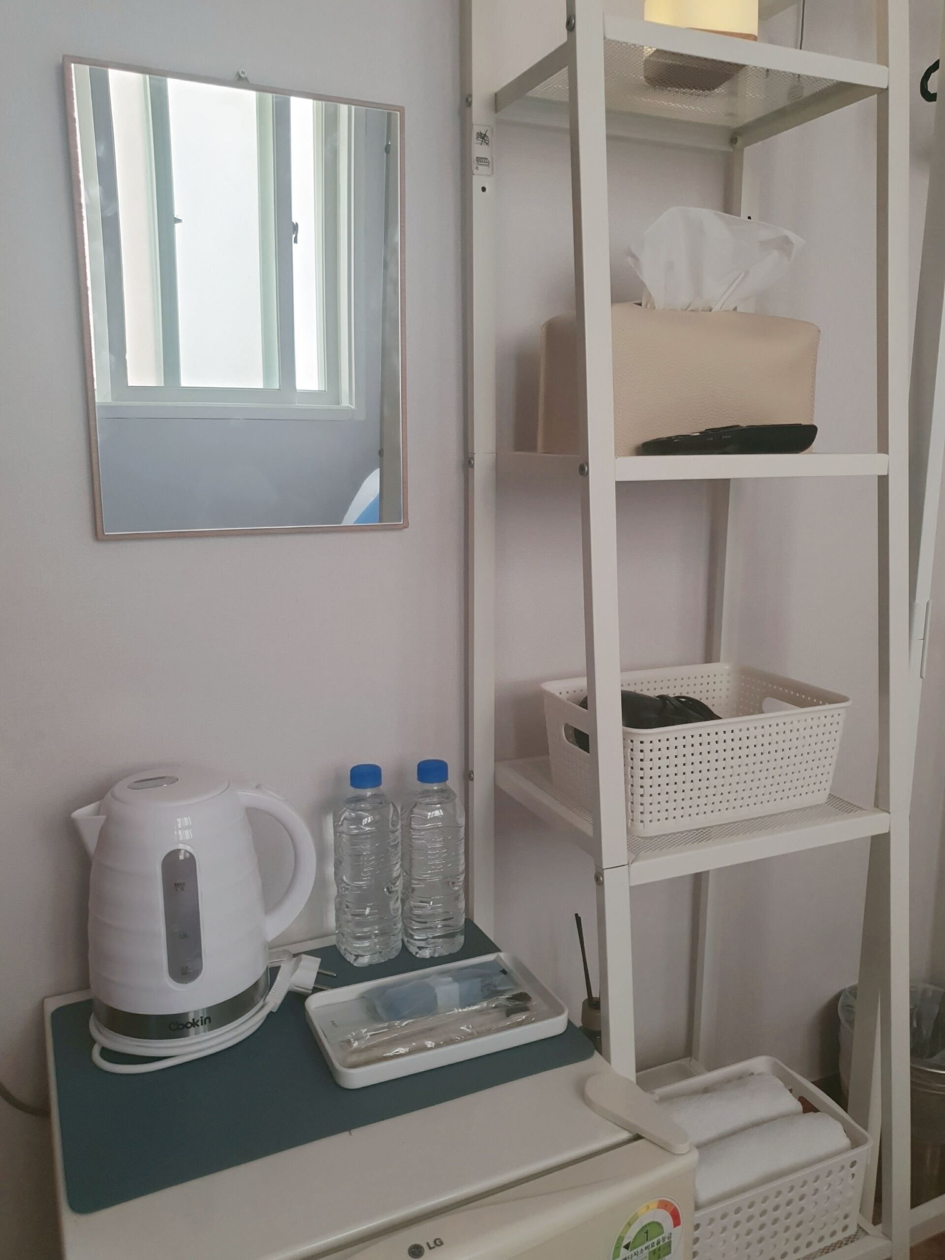 A kitchenette with a kettle, two water bottles, a scale, and a microwave.