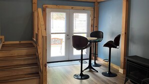 A spacious room with a wooden staircase, a dining area with two chairs, and a black fireplace. - Clinch Mountain Reserve Cabin #2.  Cabin retreat near charming Rogersville, TN. (Rogersville)