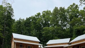 Two wooden cabins with metal roofs, surrounded by a stone wall and a dirt path. - Clinch Mountain Reserve Cabin #2.  Cabin retreat near charming Rogersville, TN. (Rogersville)