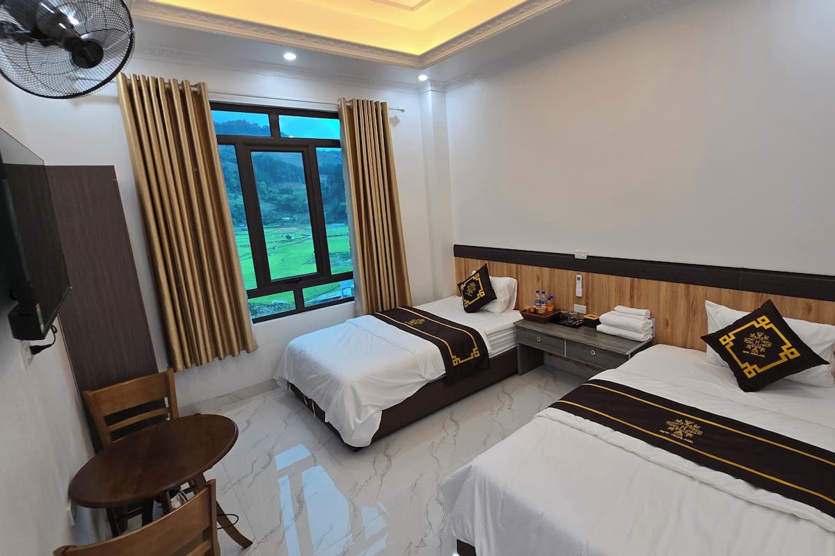 A hotel room with two beds, a desk, a chair, a TV, and a window with curtains.