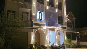A multi-story building with illuminated exterior lights, large windows, and a balcony. - New Highland Hotel (Mu Cang Chai)