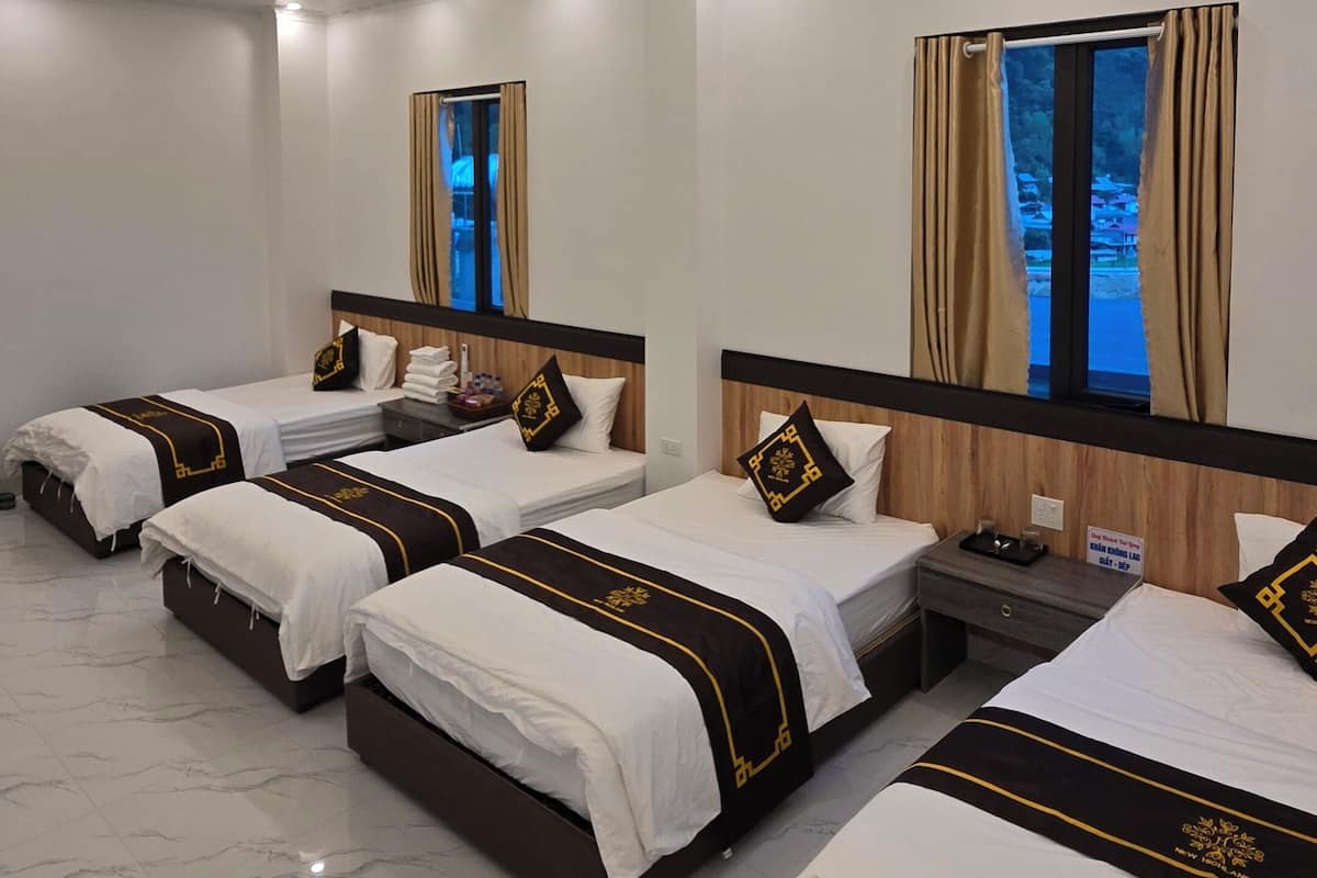 A hotel room with four beds arranged in a row, a large window with curtains, and a marble floor.