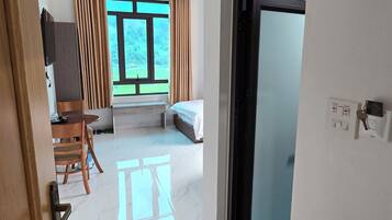 Una habitación de hotel moderna con un ventanal grande, una cama, un escritorio y una silla.