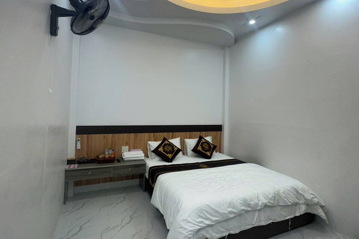 A modern bedroom with a bed, bedside table, and a wall-mounted fan.