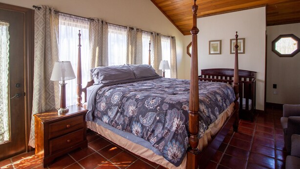 A bedroom with a four-poster bed, wooden headboard, and a ceiling fan. - Private Room w Shared Pool Hot Tub and Fire Pit (Bloomington)