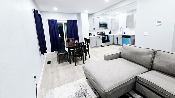 A modern apartment with a dining area, kitchen, and living room. - 3-Bedroom House Close to Pacific University (Forest Grove)