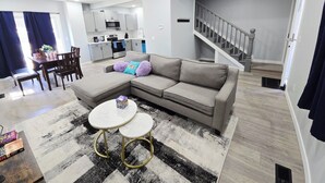 A modern living room with a grey sectional sofa, a white round coffee table, and a black and white rug. - 3-Bedroom House Close to Pacific University (Forest Grove)
